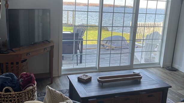 A living room with a large window overlooking a body of water, a television, and a cozy seating area.