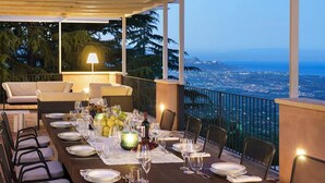 Tavola imbandita per sei con vista sulla città al crepuscolo.