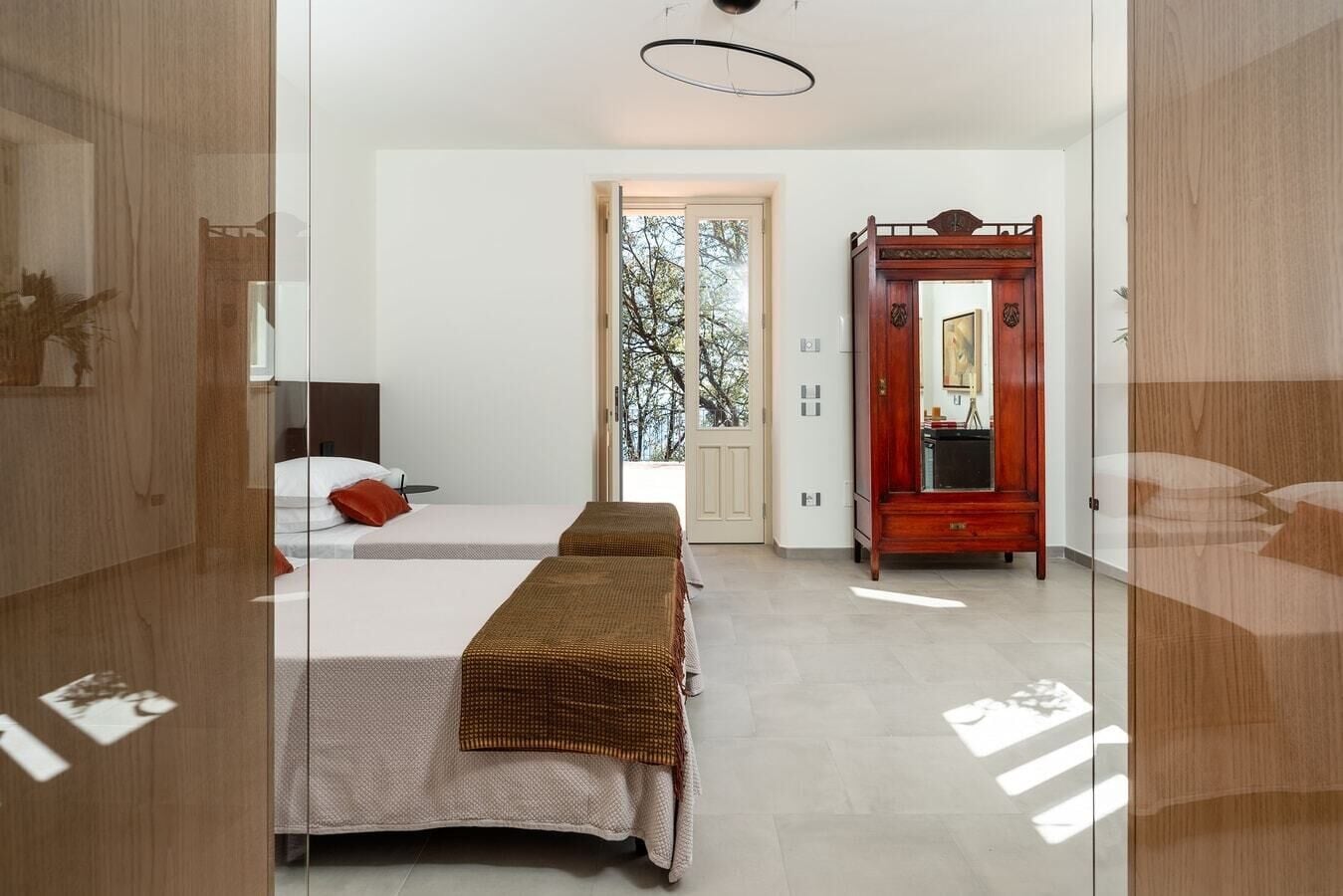 Ein Schlafzimmer mit zwei Betten, einem Holzschrank und einem großen Spiegel.