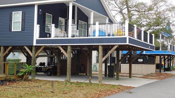 A two-story house with a balcony, a covered porch, and a garage. - V29 Family-friendly 3BR w/ Outdoor Kitchen + 2 Lounges, Limo Golf Cart (Myrtle Beach)
