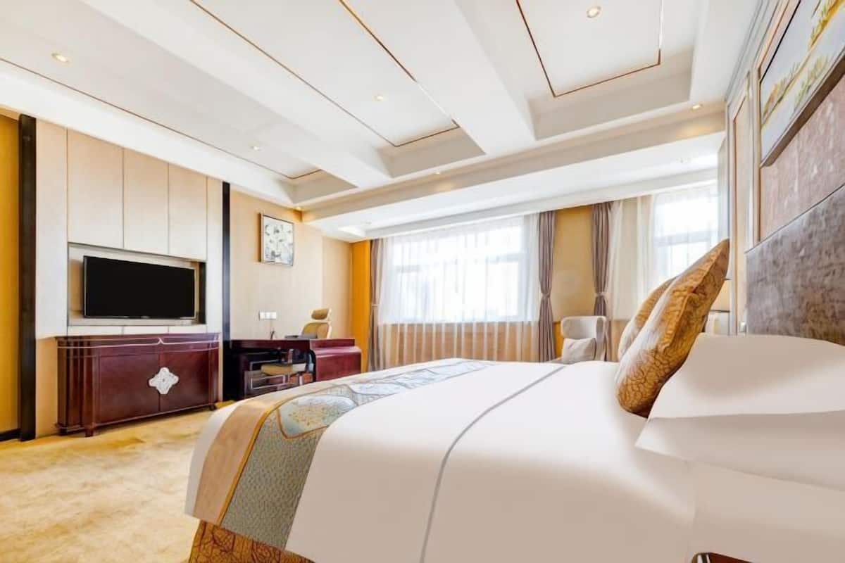 Habitación de hotel con una cama grande, televisión de pantalla plana, escritorio y ventana con cortinas.