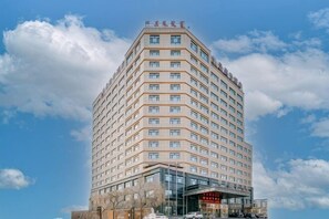 A multi-story hotel with a modern design, featuring a prominent entrance and a clear sky in the background.