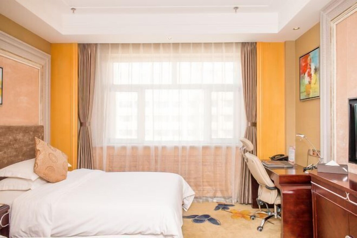 Una habitación de hotel con cama, escritorio, silla y televisión.