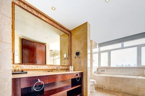Un baño moderno con un espejo grande, un tocador con lavamanos y una bañera.