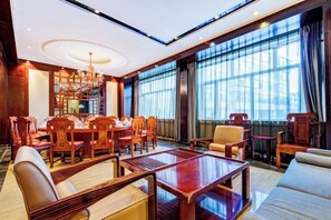 A spacious hotel lobby with a dining area, seating arrangements, and large windows.
