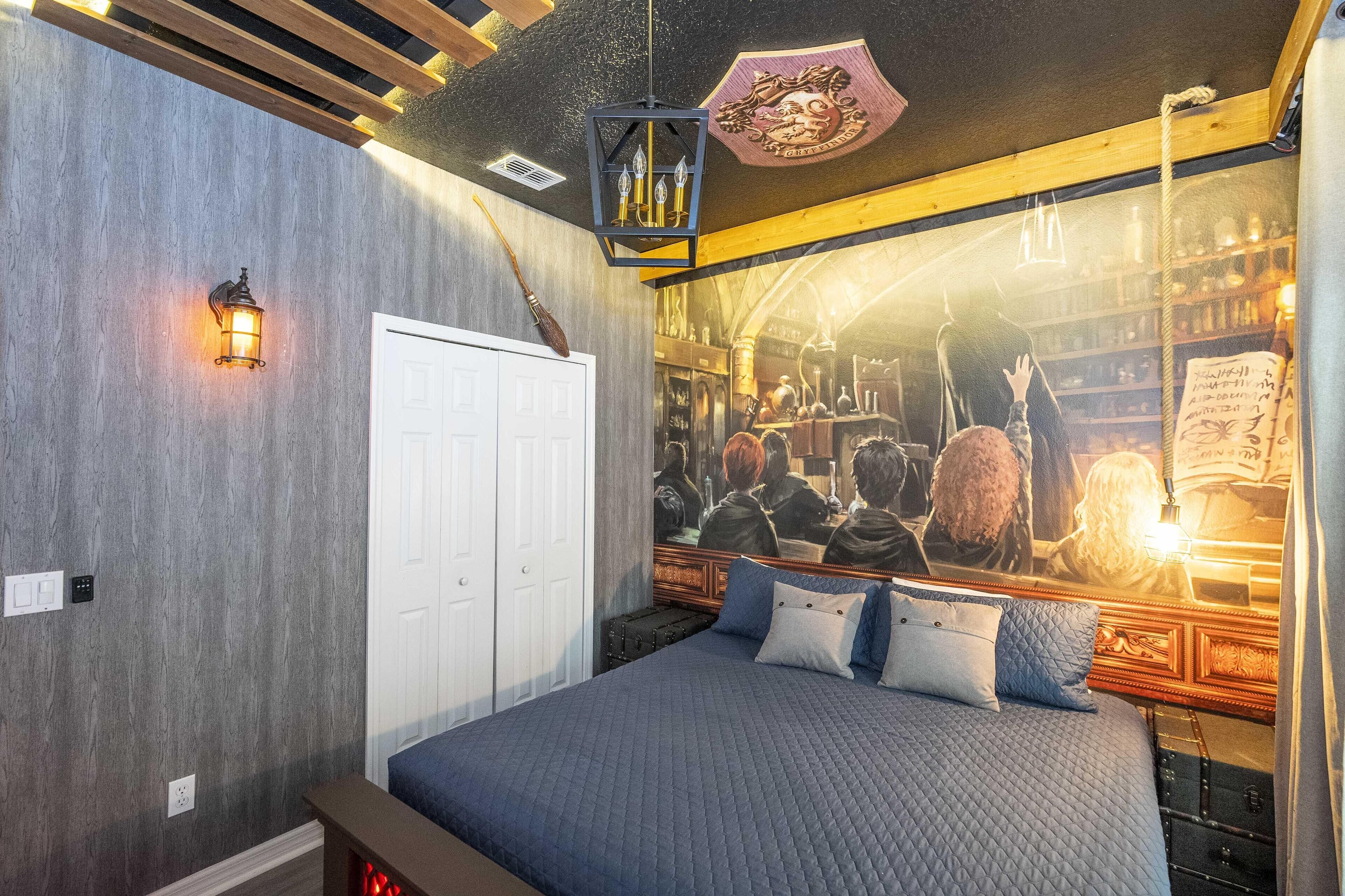 A bedroom with a large bed, a wardrobe, a mirror, and a wall with a mural.