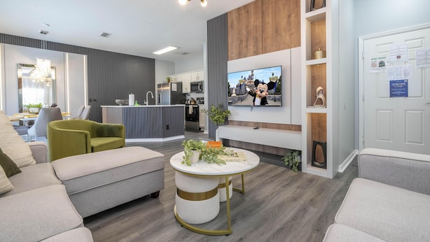 Ein modernes Wohnzimmer mit einer Couch, einem Sessel und einem runden Couchtisch mit Dekoration.