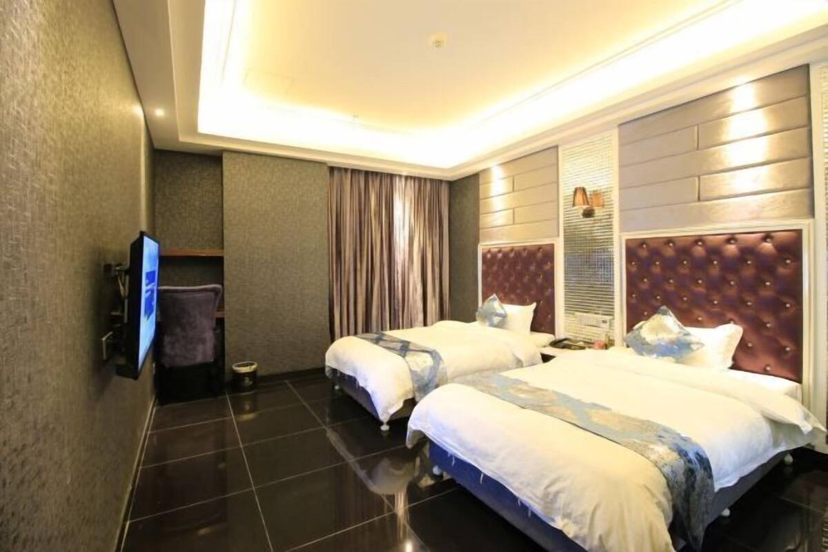 A hotel room with two beds, a flat-screen TV, a large mirror, and a modern design.
