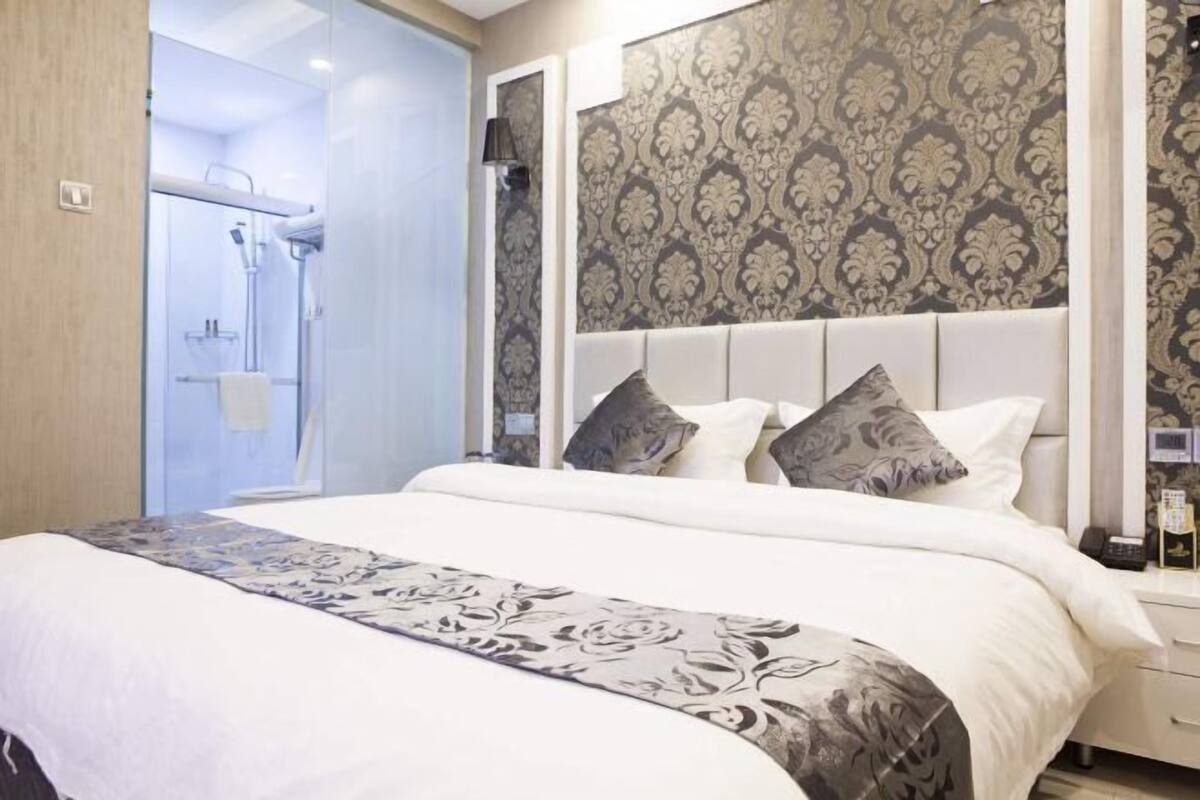 A bedroom with a large bed, a headboard, and a shower area.