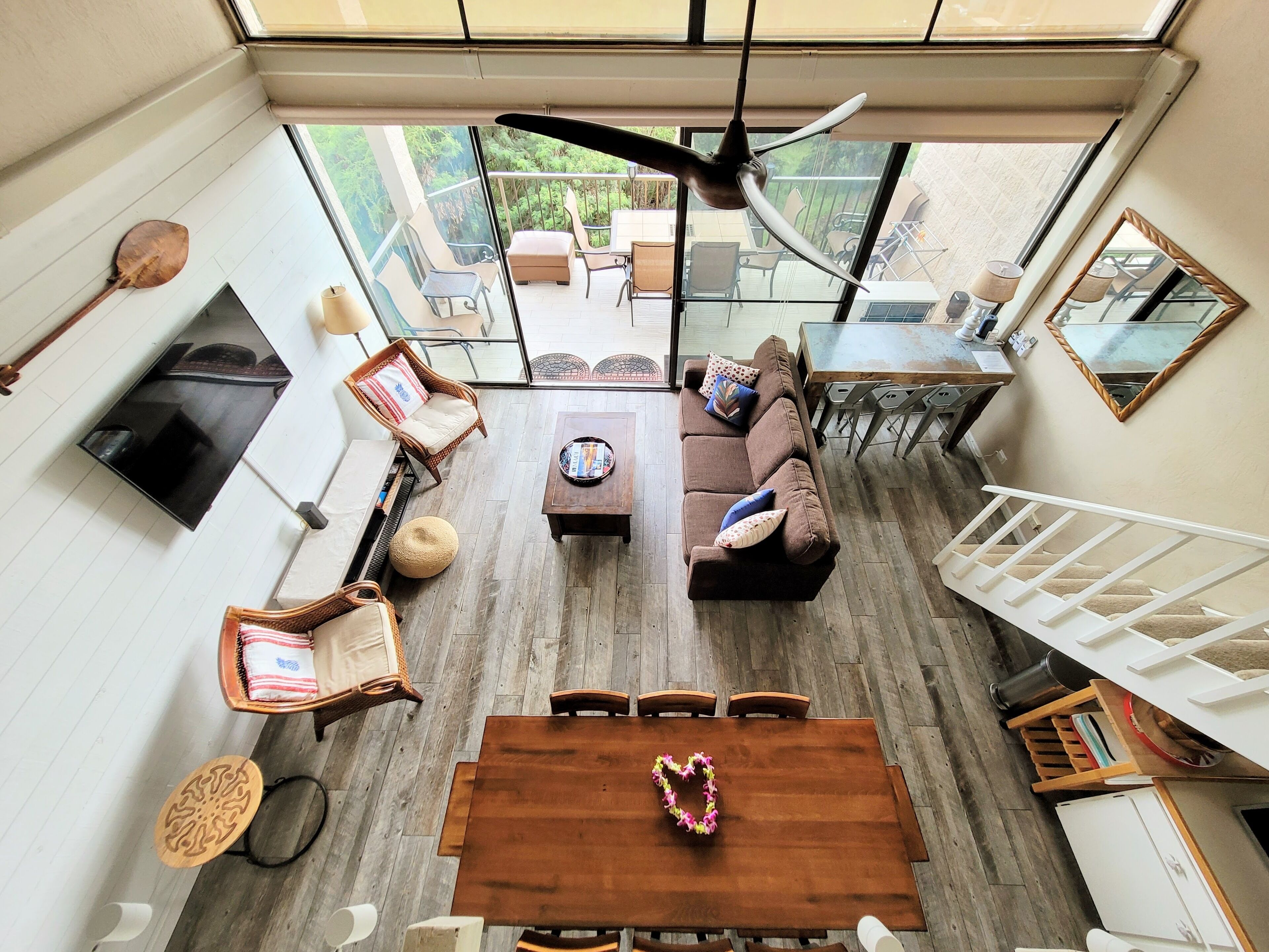 A spacious living area with a wooden dining table, a sofa, and a ceiling fan.
