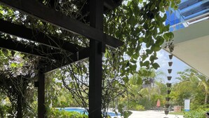 Un espacio al aire libre cubierto con piscina, rodeado de follaje y una vista despejada del cielo.