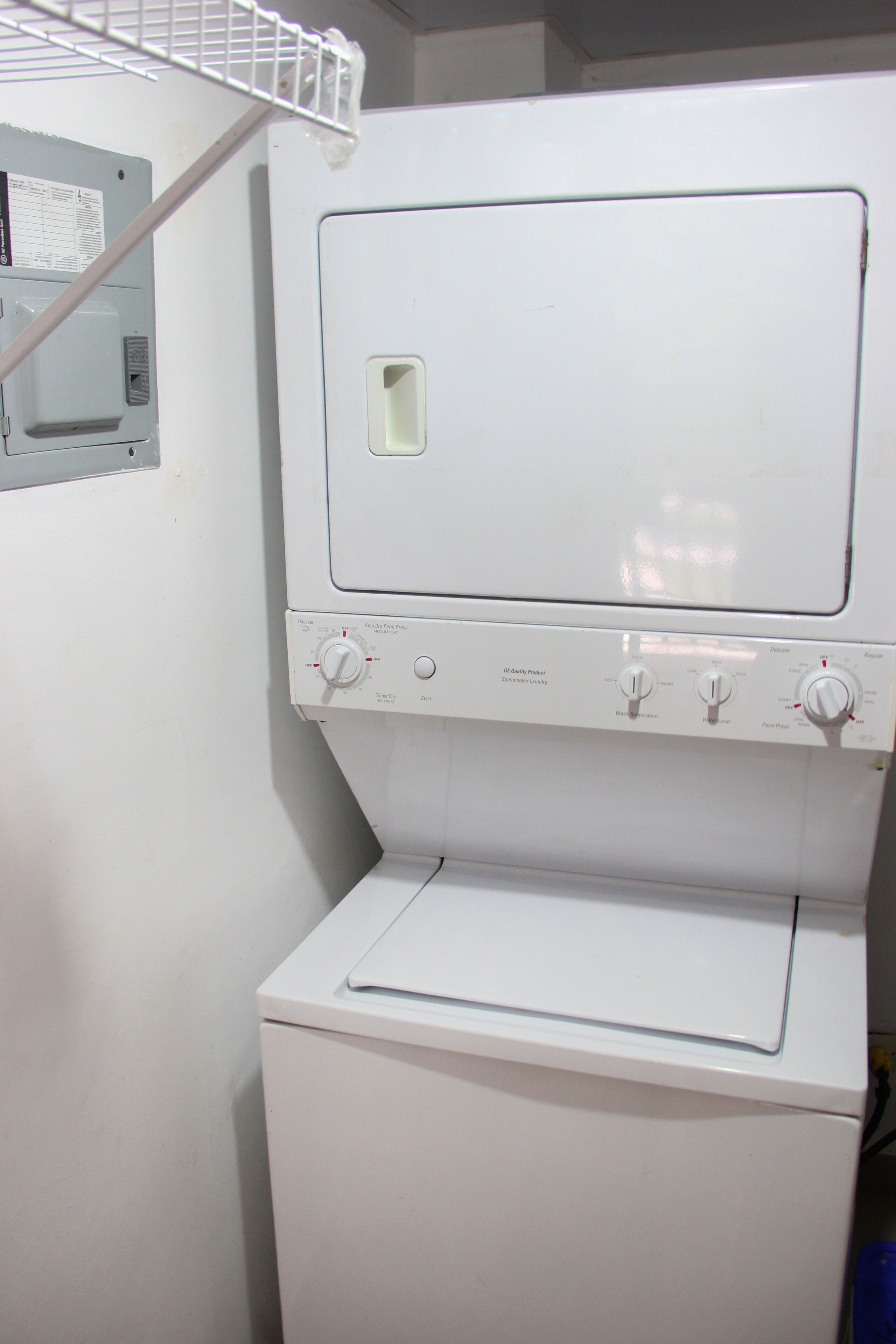 A front view of a white laundry machine with control knobs and a small window on the top.
