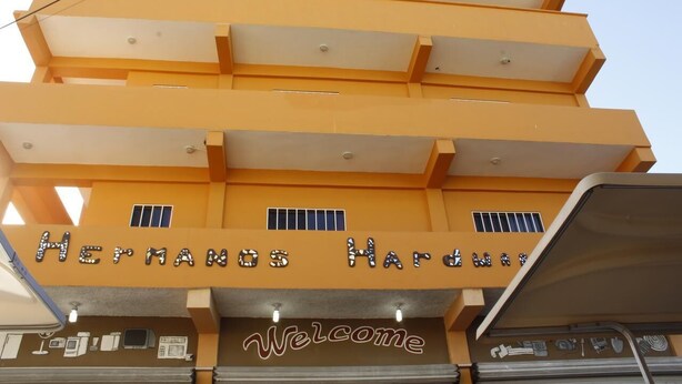 En bygning med flere etager med en gul facade og et 'Welcome'-skilt ved indgangen.