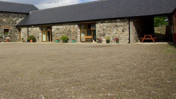 A stone building with a gravel driveway and a wooden bench.