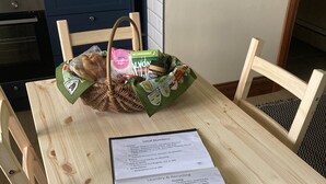 A wooden dining table with a basket of groceries and a laundry & recycling guide.