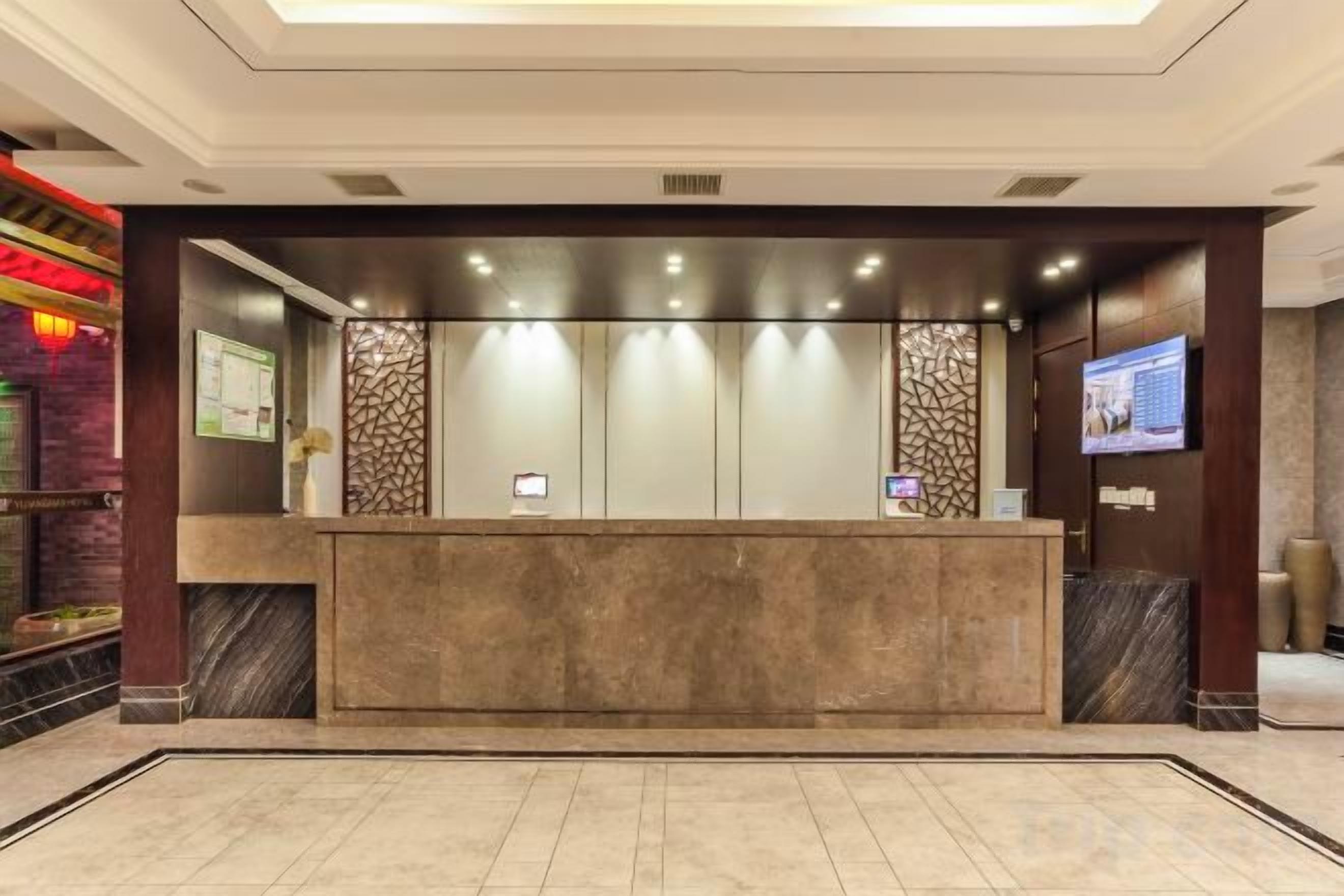 A reception area with a marble counter, a television screen, and a decorative wall.