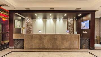A reception area with a marble counter, a television screen, and a decorative wall.
