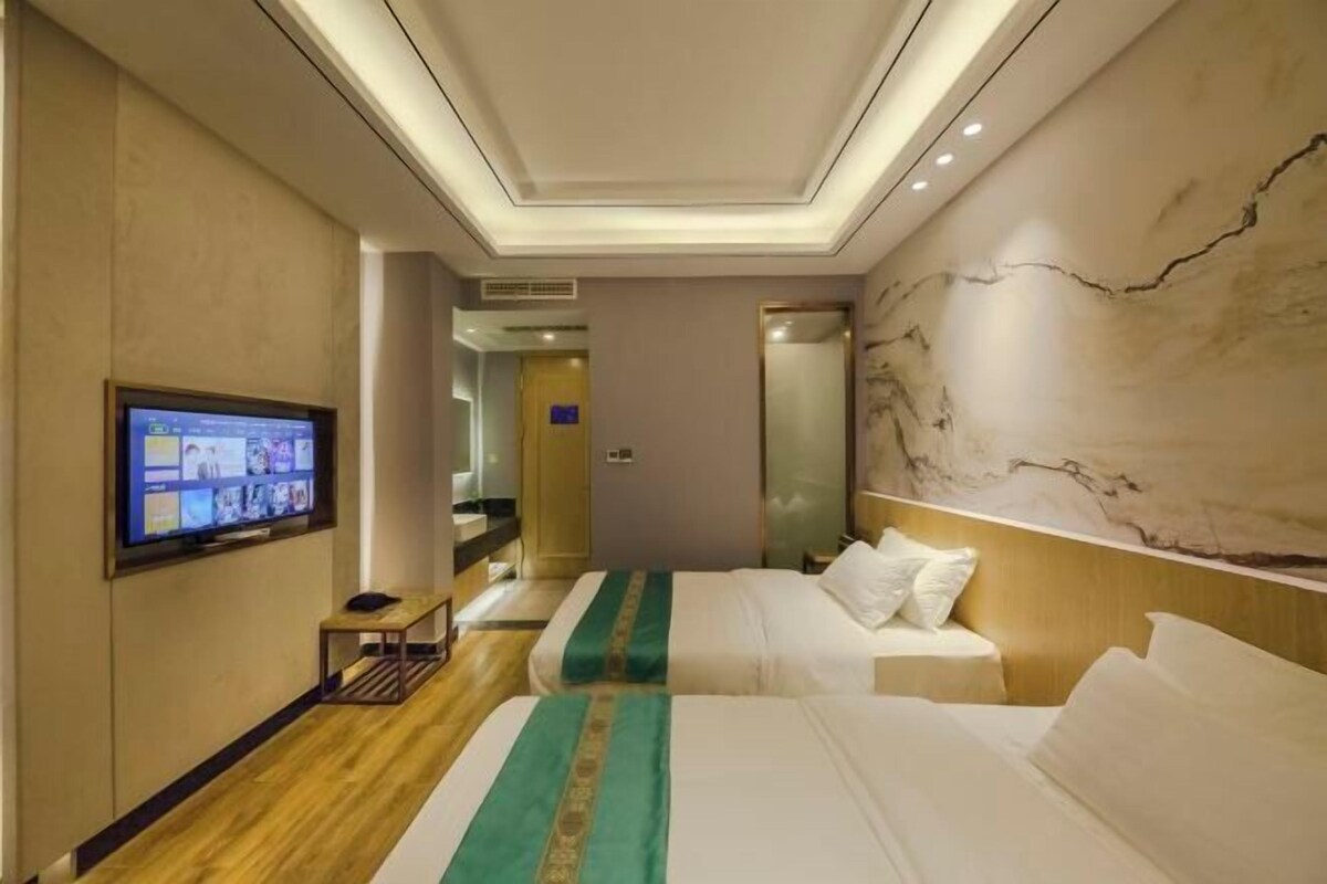 Ein Hotelzimmer mit zwei Betten, einem an der Wand befestigten Fernseher und einer Marmorwand.