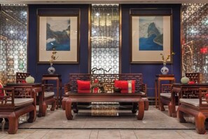 A traditional room with a central wooden sofa, multiple chairs, and a decorative screen. - Yijiangnan Selected Hotel (Yuyao)
