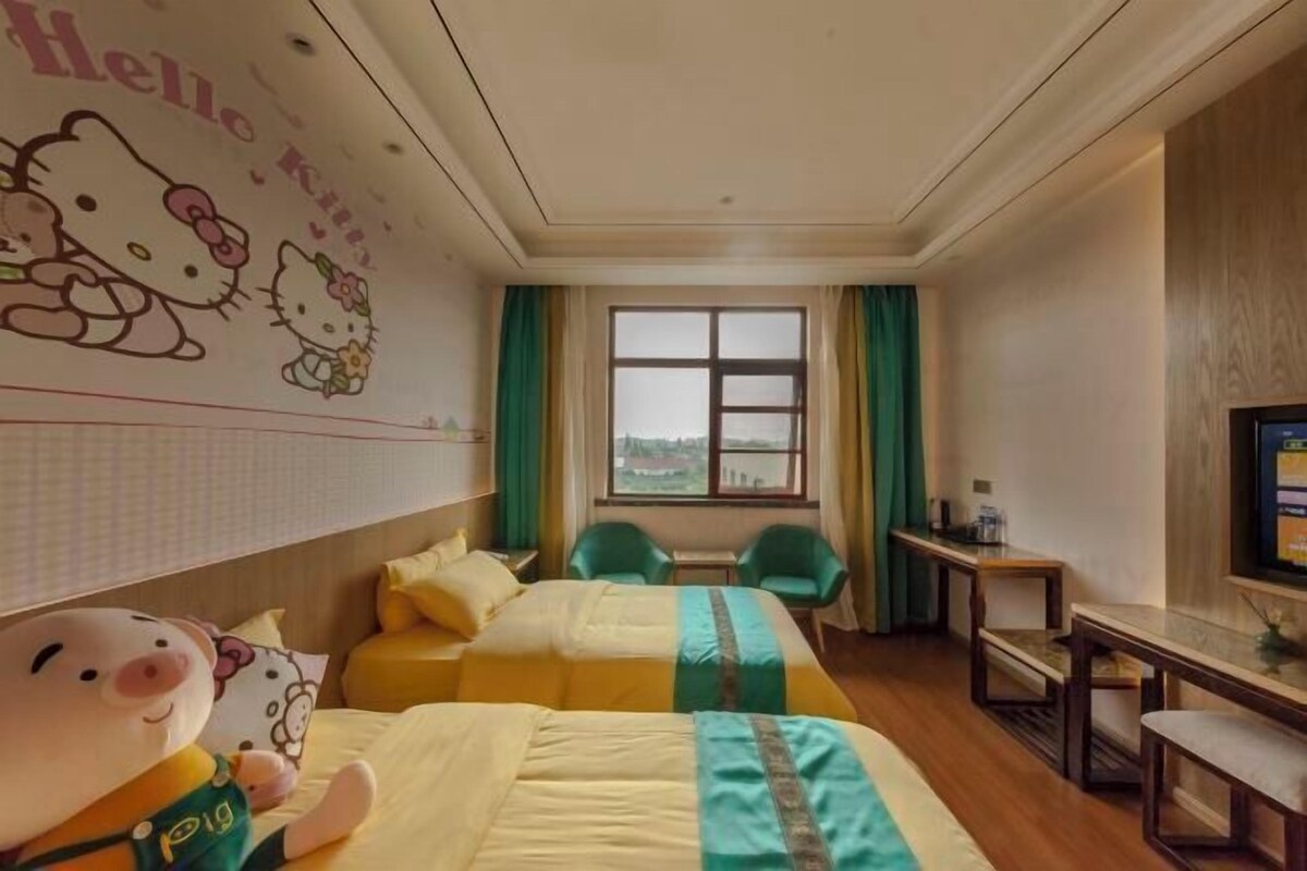 Ein Hotelzimmer mit zwei Betten, einem Schreibtisch, einem Fernseher und einem Fenster mit Vorhängen.