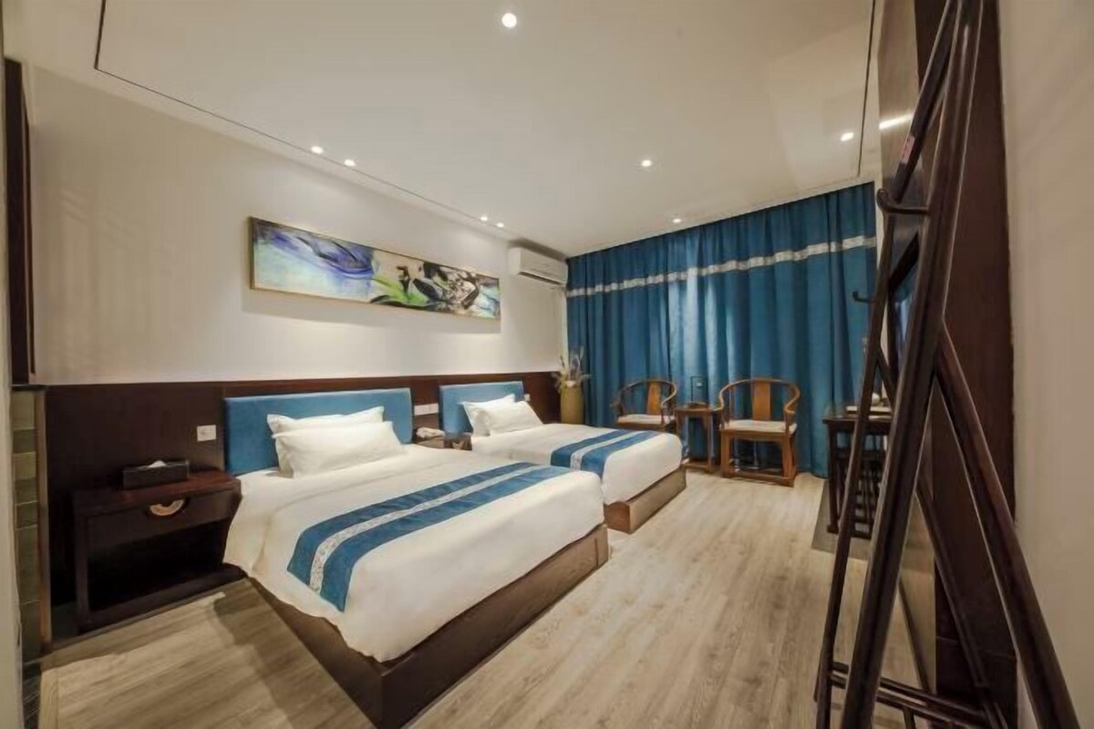 Ein Hotelzimmer mit zwei Betten, einem Schreibtisch und einem Stuhl.