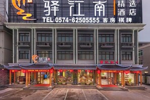 A hotel with a traditional Chinese architectural style, featuring a large signboard with contact information and a modern facade. - Yijiangnan Selected Hotel (Yuyao)