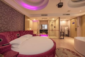 Ein modernes Hotelzimmer mit einem großen Bett, einem rosa Schlafsofa, einer Badewanne und einer Duschkabine.