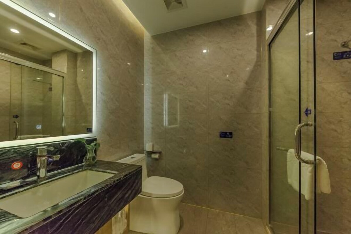 Ein modernes Badezimmer mit Duschkabine aus Glas, Marmorwaschbecken und Toilette.