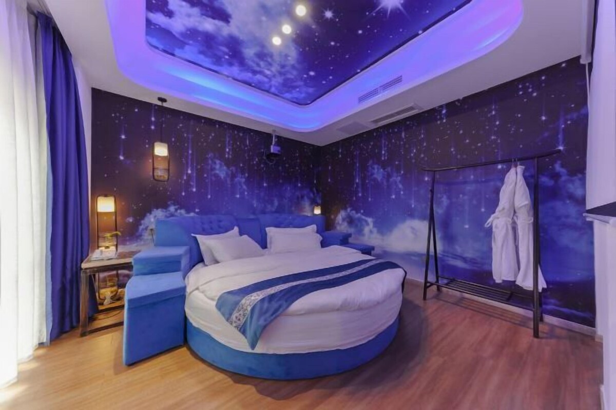 Ein Schlafzimmer mit Sternenhimmel-Decke, einem runden Bett, einem Nachttisch und einem Kleiderständer.