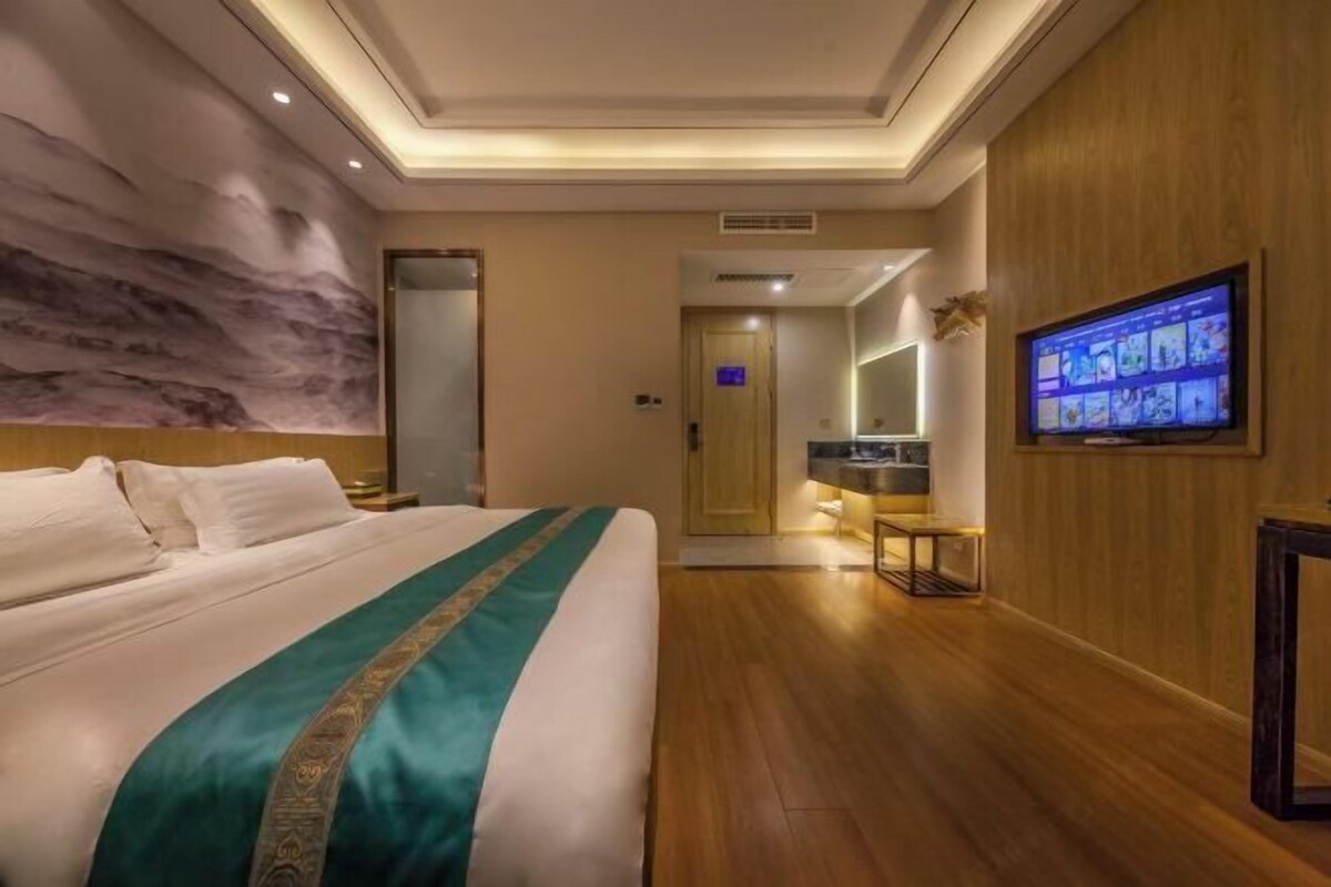 Ein Hotelzimmer mit einem großen Bett, einem an der Wand befestigten Fernseher und Holzboden.