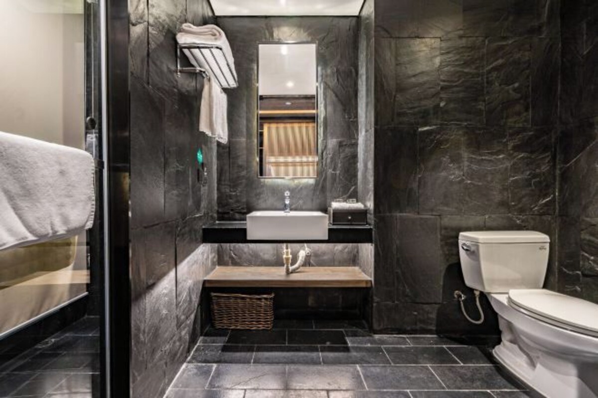 A modern bathroom with a marble wall, a sink, a toilet, and a towel rack.