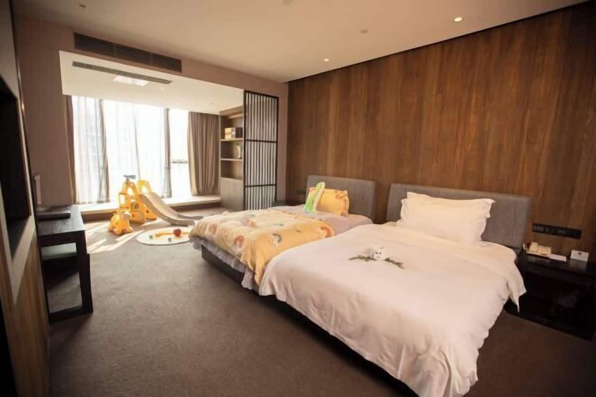 A modern hotel room with a large bed, a desk, and a play area with toys.