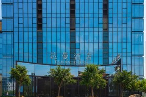 Un moderno edificio de hotel con fachada de vidrio reflectante y un letrero que indica que es el Taman Hotel.