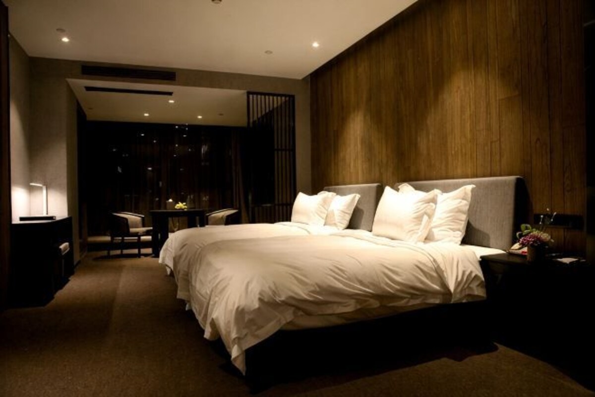 A modern hotel room with a large bed, a desk, and a chair.