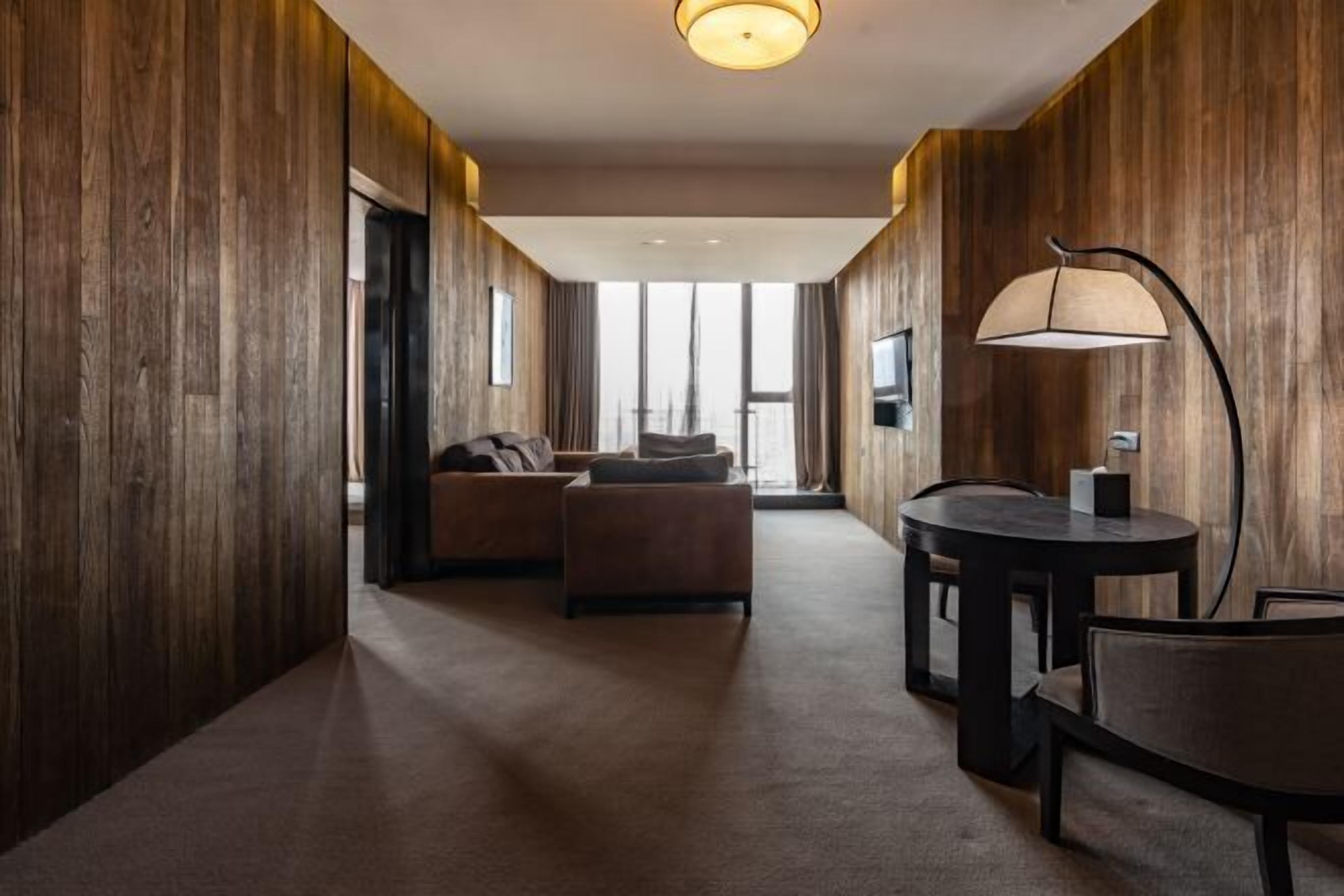 Une chambre d’hôtel avec un intérieur en bois, un canapé, une table ronde et une lampe.