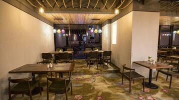 A restaurant interior with tables and chairs, a patterned carpet, and hanging lights.