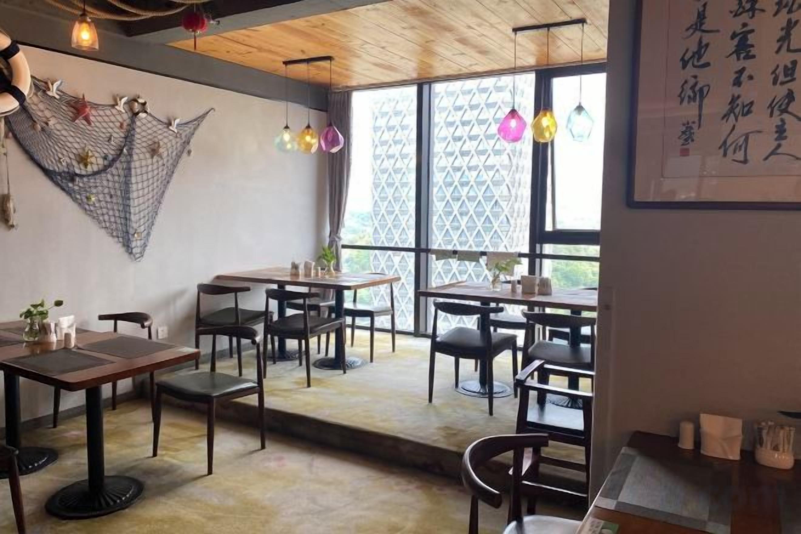 A restaurant interior with tables and chairs, a hammock, and a large window.