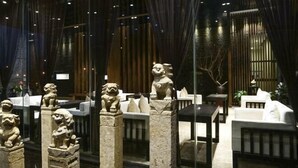 Una habitación con estatuas de leones de piedra, un sofá blanco y una mesa con lámpara.