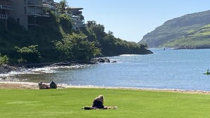 A coastal hotel with a grassy lawn, a rocky shoreline, and a view of the sea. - Oceanfront home on one of the most popular beaches in Kauai! (Lihue)