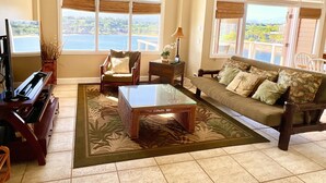 A living room with a piano, a sofa, a coffee table, and a view of the ocean. - Oceanfront home on one of the most popular beaches in Kauai! (Lihue)