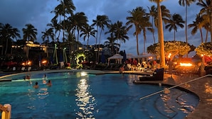 A swimming pool with people in the water, surrounded by palm trees and lounge chairs. - Oceanfront home on one of the most popular beaches in Kauai! (Lihue)