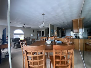 A spacious living room with a large wooden dining table, leather sofas, and a kitchen area with modern appliances.