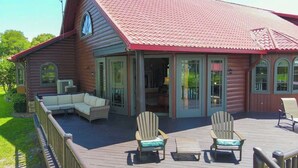 A wooden cabin with a deck, outdoor seating, and large windows.