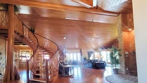A spacious interior with a wooden staircase, a dining area, and a large window providing natural light.