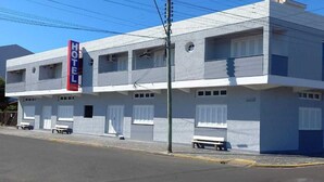 Un hotel de dos plantas con un llamativo letrero 'HOTEL', numerosas ventanas y una fachada plana.