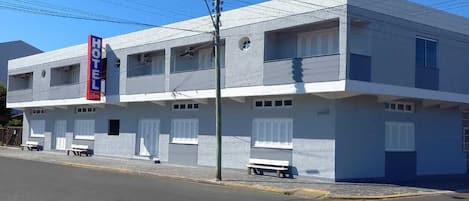 Un hotel de dos plantas con un llamativo letrero 'HOTEL', numerosas ventanas y una fachada plana.