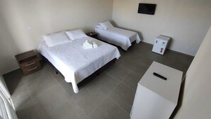 Una habitación con dos camas, un escritorio pequeño y un armario.