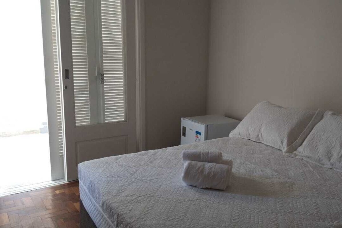 Un dormitorio con una cama, almohadas, una mesita de noche y un calentador blanco.