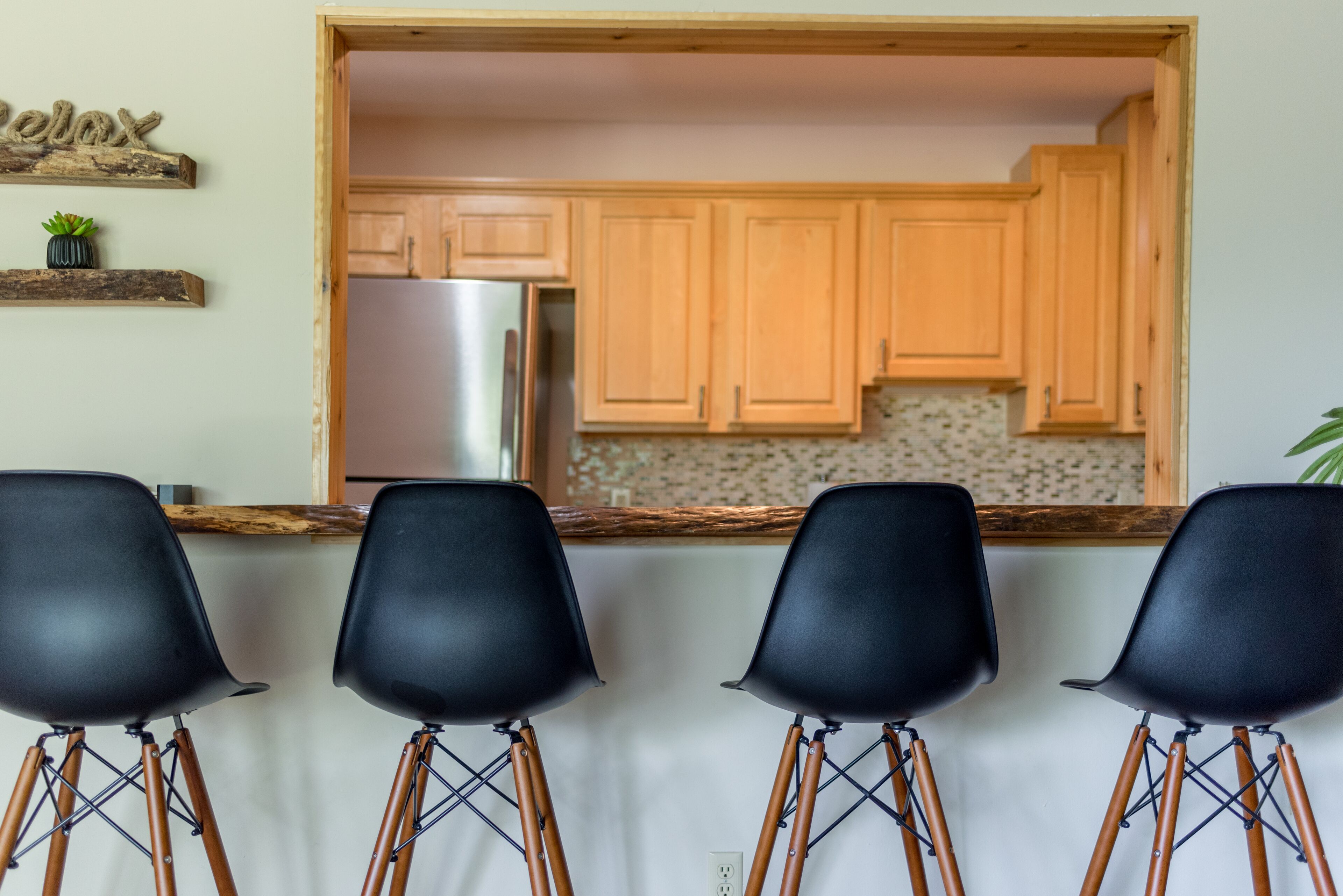 Eine Küche mit Holzausstattung, einem Edelstahlkühlschrank und einer Arbeitsplatte mit einem Blumentopf.