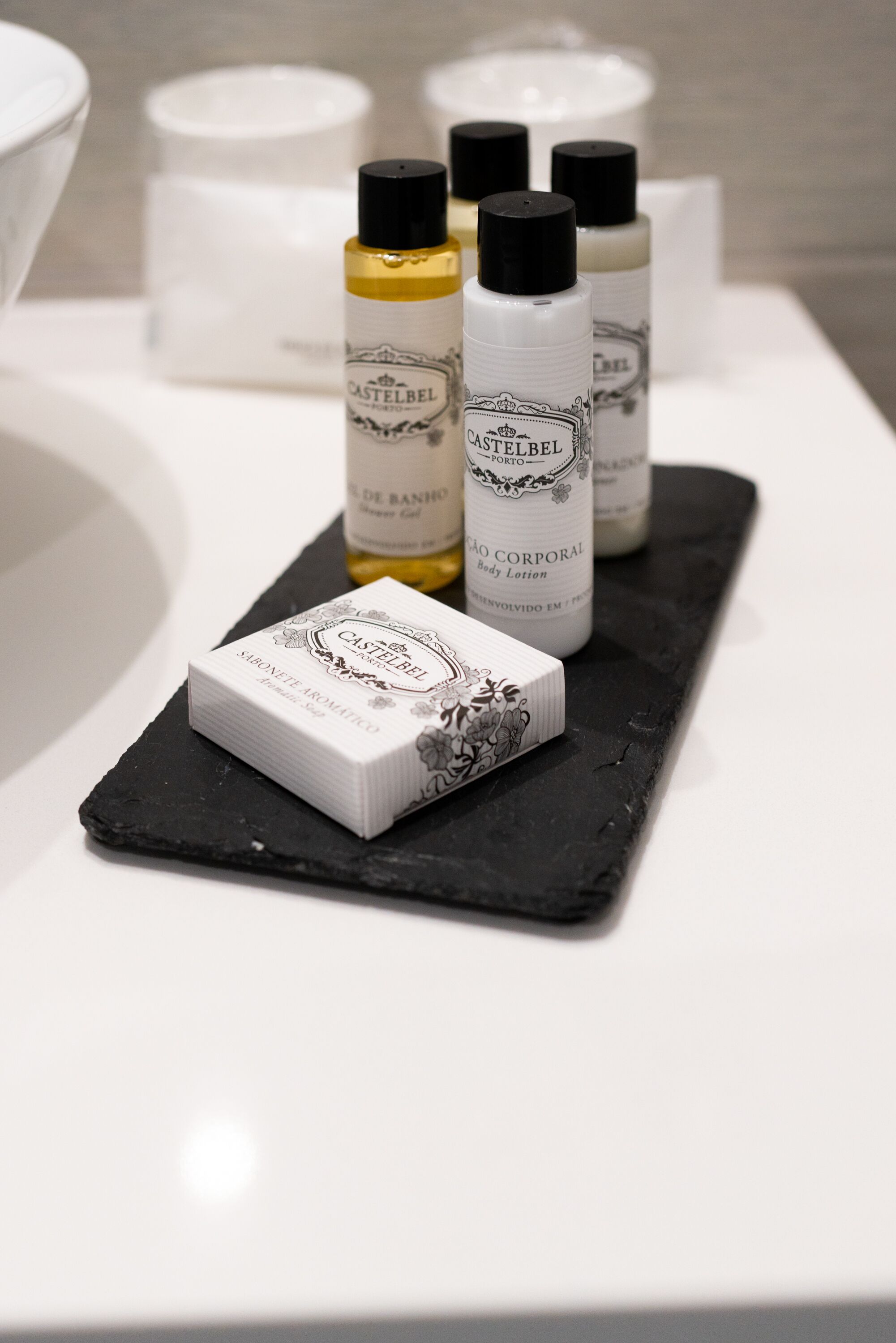 Uma bancada de banheiro com produtos de higiene pessoal, incluindo loção corporal e sabonete.